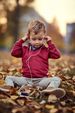 mutlu çocuk akıllı telefonda müzik dinlemek. Aile, çocukluk, mevsim ve insan kavramı