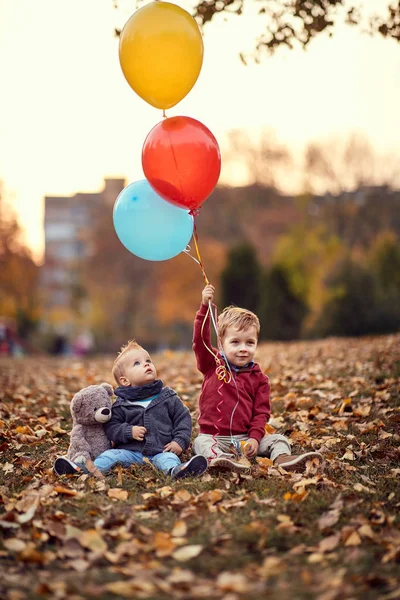 Pequeño niño. Otoño dorado. Día soleado. niños jugando con globos en el parque de otoño — Foto de Stock