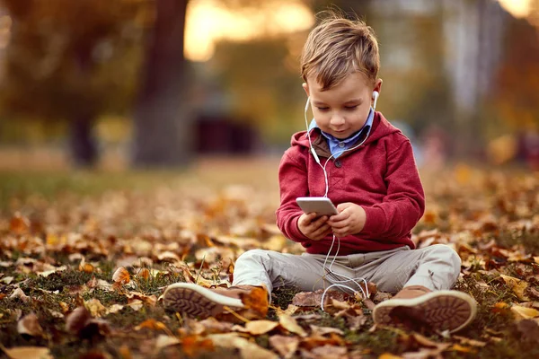 Menino criança ouvir música no smartphone ao ar livre — Fotografia de Stock