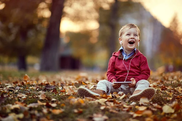 Lachende Kid luisteren muziek op smartphone. Familie, jeugd, seizoen en People concept — Stockfoto