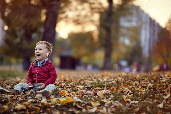 Niño feliz escuchar música en el teléfono móvil en el parque — Foto de Stock