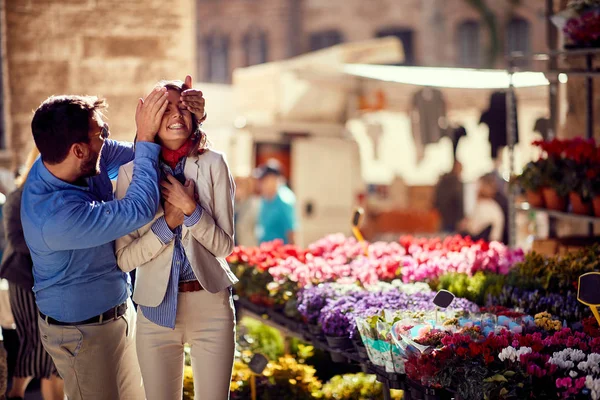 Junger Mann überrascht Frau in Blumenladen auf der Straße — Stockfoto