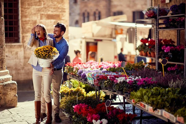 Jeune homme surprend fille pour les plantes à la boutique de fleurs dans la rue — Photo