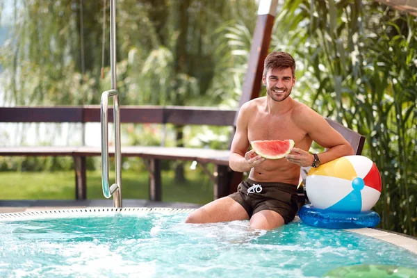 Homem refrescante com melancia na piscina — Fotografia de Stock