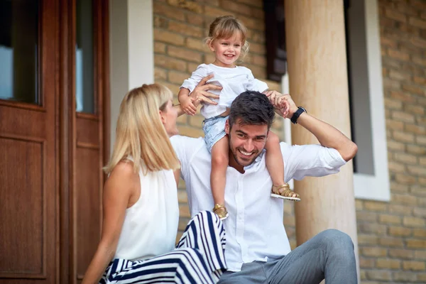 Küçük kız babasının omuzlarında oturuyor. 