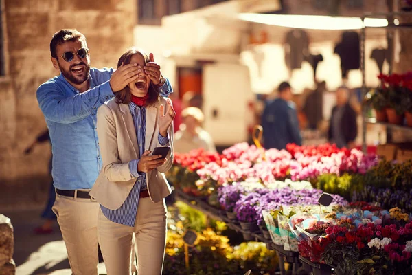 Чоловік дивує жінку в квітковому магазині на вулиці — стокове фото