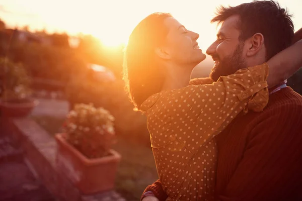 Lachend koppel knuffelen en kussen bij zonsondergang — Stockfoto