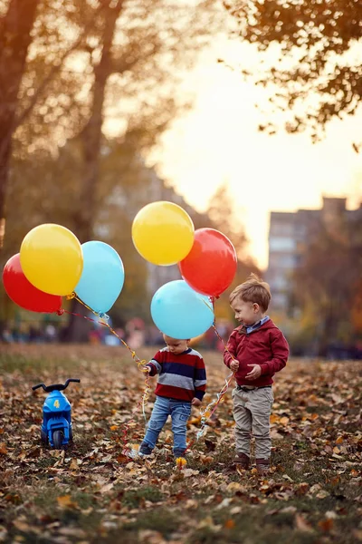 Niños hermanos jugando juntos en el parque de otoño con globos . — Foto de Stock