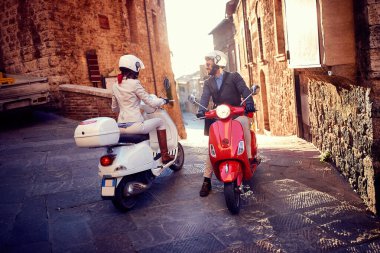 Vespa Scooter 'daki genç adam ve kadın. Bisikletli çift.