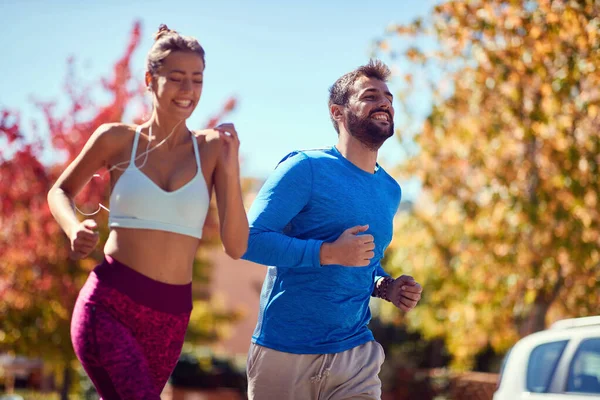 公園で若い男と女がジョギングしている。健康的なライフスタイル. — ストック写真
