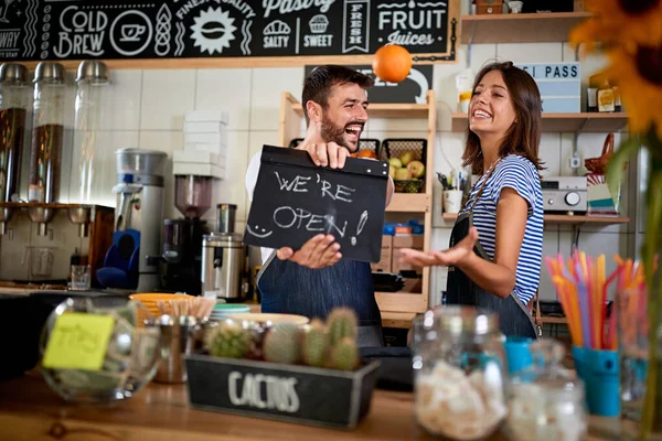 Владелец бизнеса держит открытый знак. Мужчина и женщина открывают свой магазин — стоковое фото