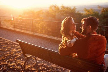 Erkek ve kadın gün batımında dışarıda öpüşüyor.