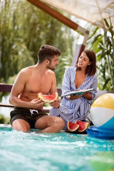 Mädchen mit Freund am Pool hält Buch — Stockfoto