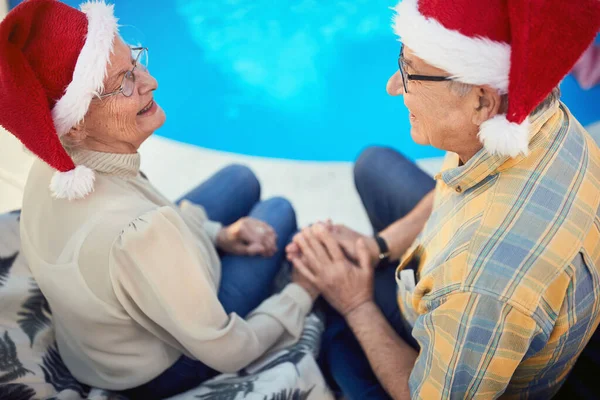 Пожилая пара в шляпах Санта-Клауса празднует Рождество — стоковое фото