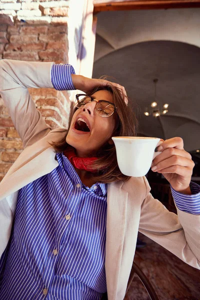 Mujer cansada trabajando en el ordenador portátil en la cafetería . —  Fotos de Stock