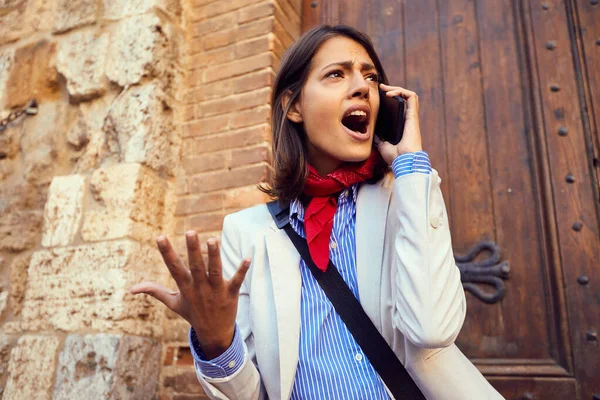 Wütende Geschäftsfrau arbeitet und telefoniert auf der Straße. — Stockfoto