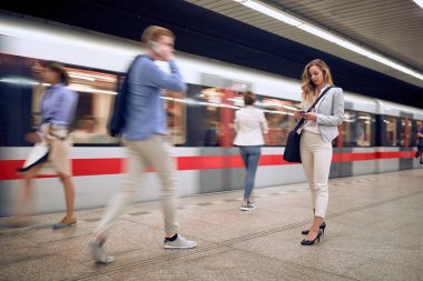 Genç bir bayan metroda cep telefonuna bakıyor. Bulanık insanlar ve tren hareket ediyor. Zaman çabuk geçiyor.