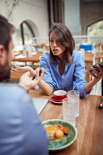 在一家拿着手机的餐厅里吵架的白人年轻夫妇 — 图库照片