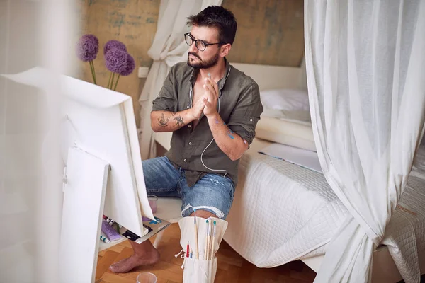 Genç yakışıklı erkek ressam işinden memnun.