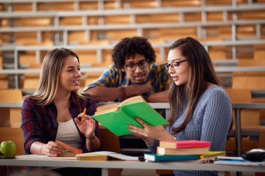 Genç üniversite arkadaşları amfitiyatroda birlikte konuşuyor.
