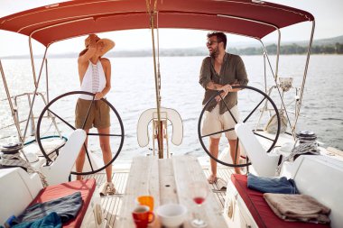 Genç mutlu kadın ve erkekler lüks bir yatta durup eğleniyorlar.