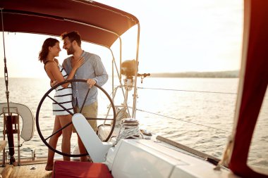 Mutlu adam ve kadın romantik günbatımında bir teknede geziyorlar..