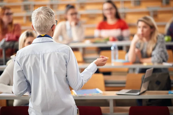 Elderly professor giving a lecture to students in amphitheater