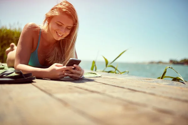 美しい笑顔の女性で水着日光浴と携帯電話上のテキストメッセージ — ストック写真