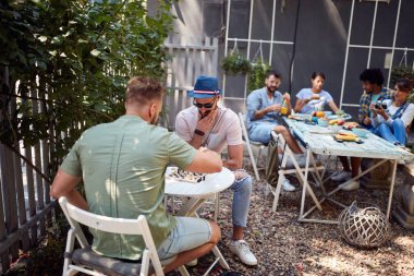 Bir grup genç, kafe bahçesinin rahat atmosferinin tadını çıkarıyor.