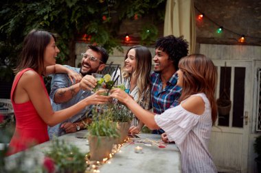 Bir grup arkadaş kafe bahçesinde kutlama yapıp kadeh kaldırıyorlar.