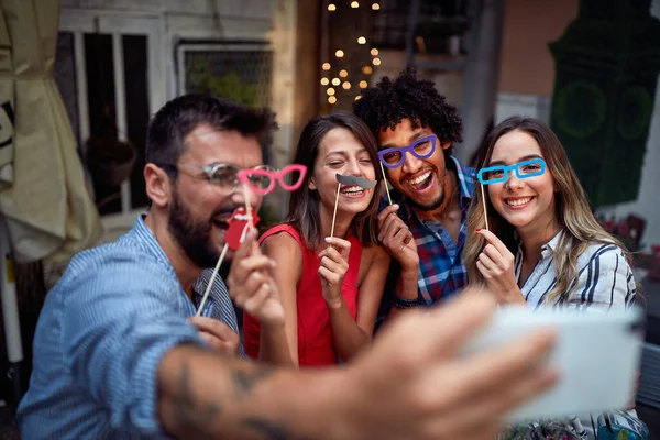 Group of young friends with funny masks taking a sefie at a party