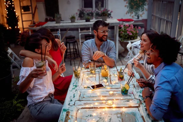 Group of friends chat having a drink together at a party