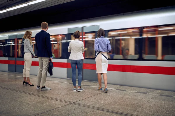 group of young business people at subway station waiting for a train.