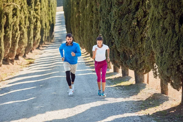 Joven Pareja Caucásica Corriendo Cuesta Arriba Camino Grava Con Árboles — Foto de Stock