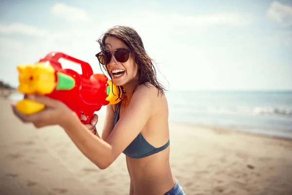 クレイジー幸せな女の子攻撃とともに水銃にビーチで休暇 — ストック写真