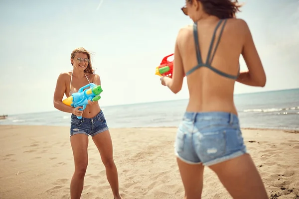 Δύο Παιχνιδιάρικες Γυναίκες Που Παίζουν Νεροπίστολα Στην Αμμώδη Παραλία — Φωτογραφία Αρχείου