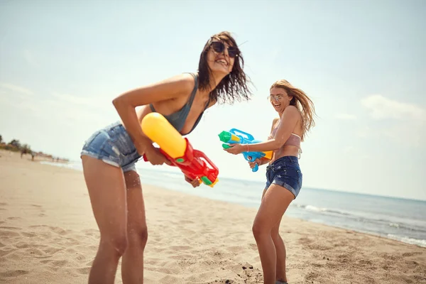 two women playing with water-guns on a beach