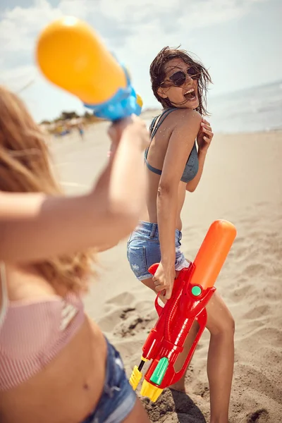 ビーチで水鉄砲を楽しんでいる若い大人の女の子 — ストック写真