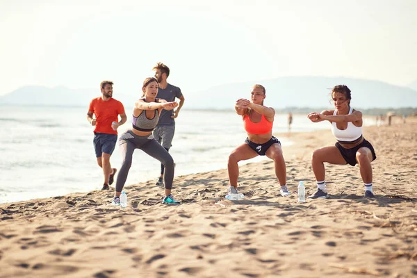 Gruppo Tre Donne Esercitarsi Una Spiaggia Sabbiosa Mentre Due Uomini — Foto Stock