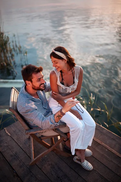 水のそばの男の膝の上に座って話して笑っている美しい女性のトップビュー コピースペース — ストック写真