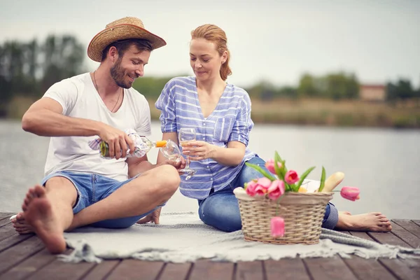 一对年轻的微笑的夫妇在野餐时喝酒庆祝 — 图库照片