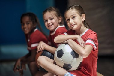 Soyunma odasında antrenmandan önce futbol topuyla gülümseyen kız..