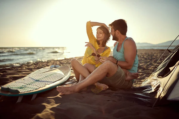 一对年轻的高加索夫妇在夕阳西下的海滩上欢欢喜喜地坐在一起 两腿交叉在一起 拥抱在一起 复制空间 — 图库照片