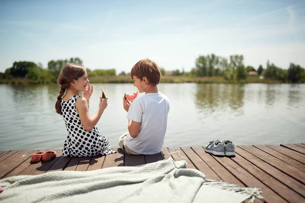 小さな白人夫婦が川のそばに座ってスイカを食べて — ストック写真