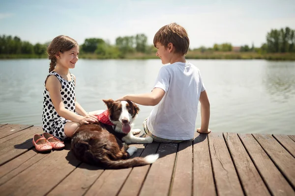 Cute Boy Girl Sitting River Smiling Cuddling Dog — Stock Photo, Image