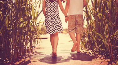 Erkek ve kız kardeş gölün rıhtımında yürüyor.