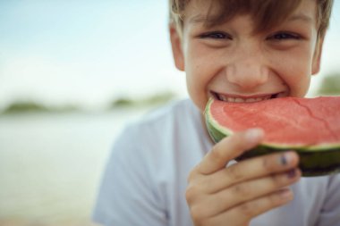 Genç çocuk sıcak bir günde tatlı karpuzun tadını çıkarıyor.