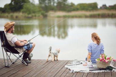 Eşler güzel bir günde köpekleriyle balık tutmayı ve piknik yapmayı severler.