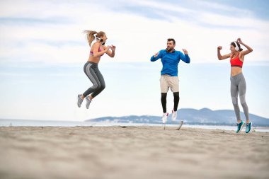 Zıplayan ve plajda spor yapan sporcular..