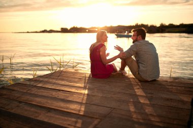 Genç aşık çift gün batımında nehir kenarında flört ediyor..